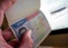 Parliament REMOVES Permanent Residence For Migrants! A hand holding an open passport displaying a visa page
