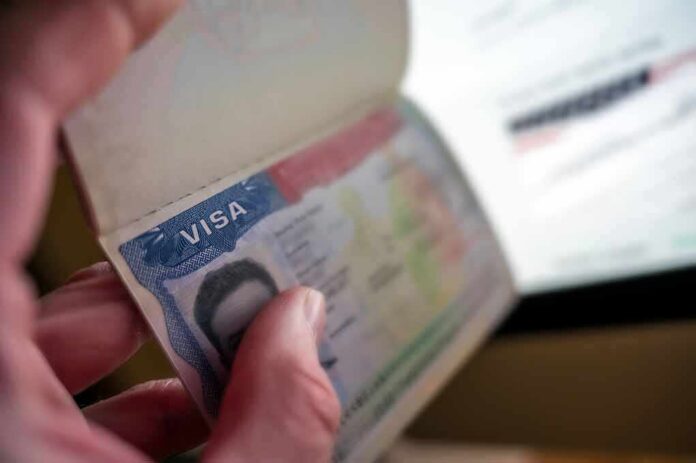 shutterstock_2559918417-1- A hand holding an open passport displaying a visa page