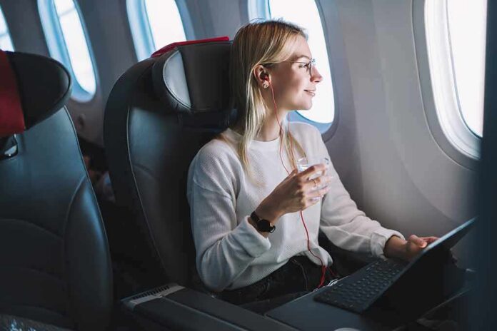 shutterstock_1321399355 Passenger with headphones seated by airplane window