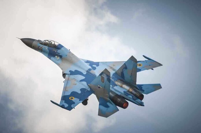 shutterstock_190311434 A blue camouflage fighter jet performing an aerial maneuver against a cloudy sky