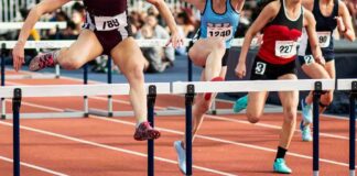 Female athletes clearing hurdles on a track