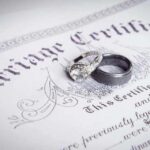 Two wedding rings resting on a marriage certificate