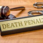 Rapper Given Death Penalty After Guilty Verdict Gavel, handcuffs, and a nameplate reading death penalty on a wooden desk