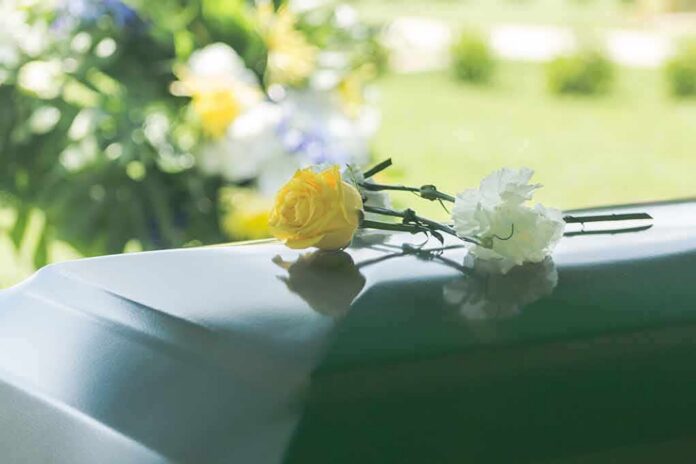 shutterstock_1014454810 Yellow rose and white carnation on a green casket