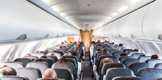Airplane cabin with passengers seated in rows