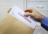Pentagon on LOCKDOWN After Catastrophic Intel Leak Hand placing confidential document into a brown envelope
