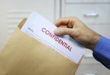 Pentagon on LOCKDOWN After Catastrophic Intel Leak Hand placing confidential document into a brown envelope