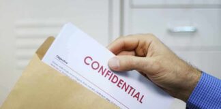 Hand placing confidential document into a brown envelope
