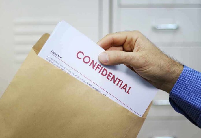 shutterstock_128095721 Hand placing confidential document into a brown envelope