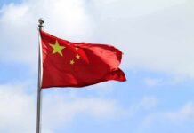 American Journalist DETAINED In China – Thrown In Prison! Chinese national flag waving on a flagpole