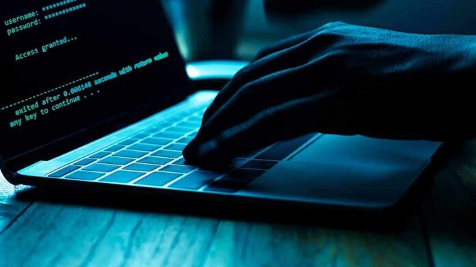Hand typing on laptop with green code on screen