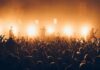 Concert Erupts After Flag Raise Rock band performing on stage with bright backlights and cheering crowd