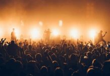 Concert Erupts After Flag Raise Rock band performing on stage with bright backlights and cheering crowd