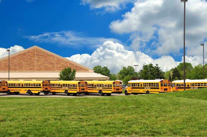 School,Bus,Lineup,In,Front,Of,The,County,School,On A row of yellow school buses parked in front of a school building under a cloudy sky