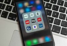 Trump YANKS Billion Dollar Lawsuit Smartphone displaying a folder of news apps on a laptop keyboard