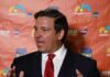 DeSantis Sounds Alarm: Institutions On The Chopping Block Man in a suit speaking at a media backdrop