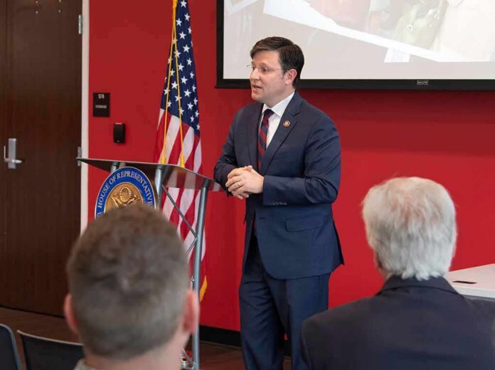 shutterstock_1381036310-1 Speaker in a navy suit addressing an audience at a podium