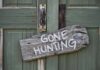 Weathered wooden sign on green door