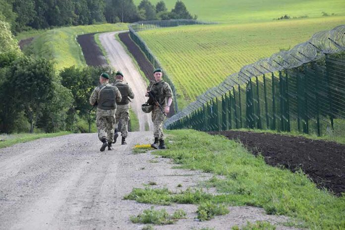 Soldiers patrolling along a rural border fence