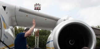 Group of people gathered near a large airplane engine