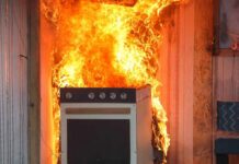 Kitchen stove engulfed in flames against a wall