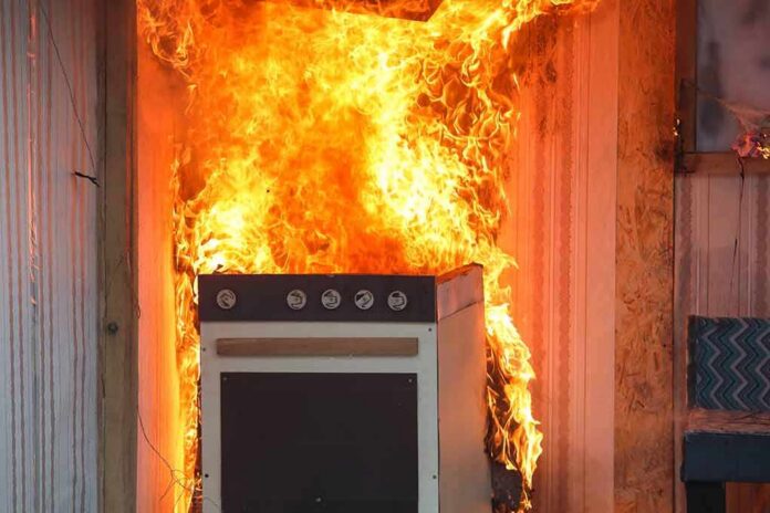 shutterstock_1519330016 Kitchen stove engulfed in flames against a wall