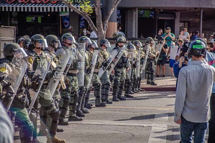 Riot police in helmets and shields form a line on a city street