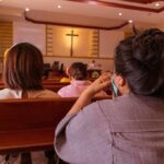 Dem Senate Candidate Slanders Virgin Mary, Denies Jesus people seated in church pews facing a cross