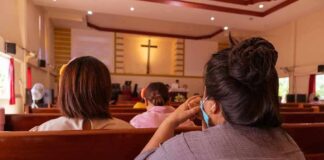 people seated in church pews facing a cross