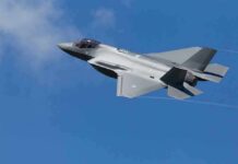 Stealth fighter jet banking in a clear blue sky