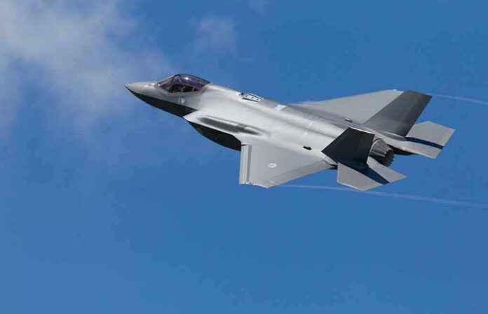 shutterstock_1803194377 Stealth fighter jet banking in a clear blue sky