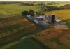 Aerial view of a farm with silos and barns amid golden crop fields