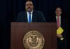 Police Gun Down Knife-Wielding Crazy in Daylight Attack Man speaks at podium with New York County District Attorney seal
