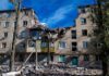 Damaged apartment building with collapsed upper floors and debris