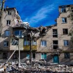 Damaged apartment building with collapsed upper floors and debris