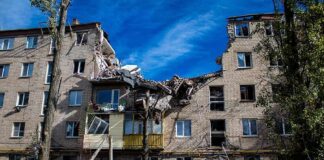 Damaged apartment building with collapsed upper floors and debris