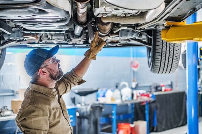 shutterstock_2246886761 Mechanic inspecting underside of a car on a lift