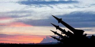 Silhouetted missiles on launchers against a colorful sunset sky