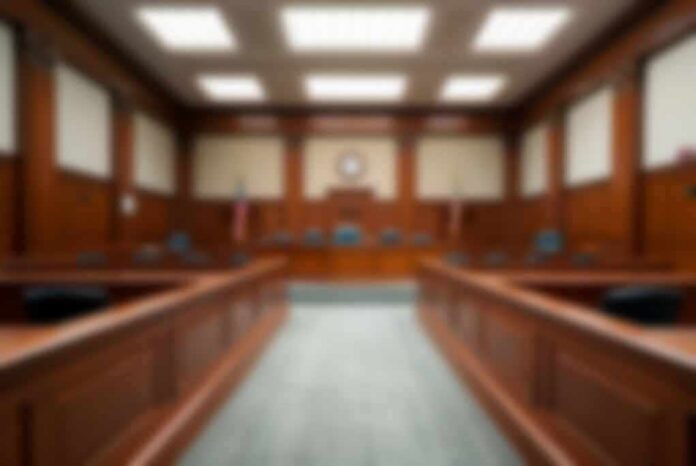 shutterstock_2324977165-1 Empty courtroom with wooden benches and judge's bench
