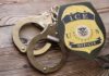 Bodycam ICE Raid Footage Exposes Fine Line ICE officer badge and handcuffs on wooden surface