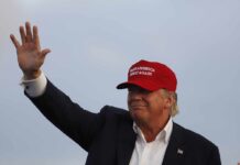 Donald Trump waving in a red cap