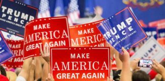 Crowd holding red and blue campaign signs at a political rally