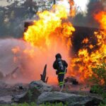 Military Inferno KILLS 4, Dozens Injured! Firefighter battling a large fire with water spray