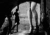 legs in high heels under an archway with blurred shadow figure