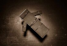 Botched Execution Chaos Stuns Onlookers Cardboard figure bound with rubber bands on a dark surface
