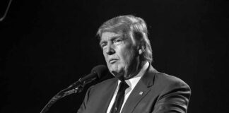 Donald Trump speaking at a microphone in a black-and-white photo